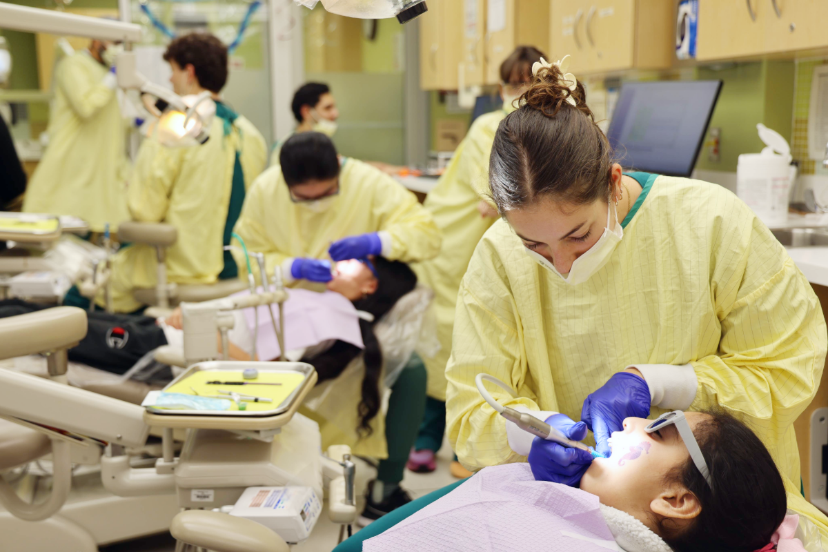 Image depicting several dental chairs all with children having dental examinations done by faculty, residents, and students in the UAB Dentistry Pediatric Clinic.