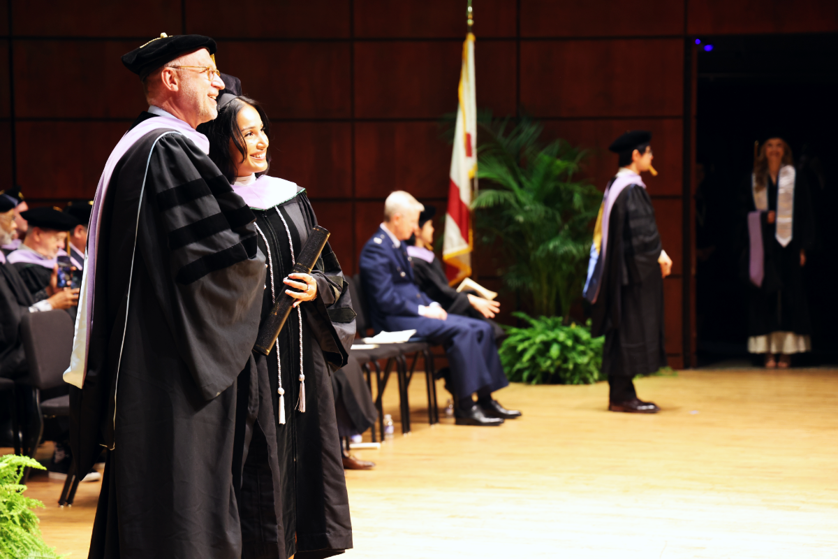 Graduate standing with Dean Geurs on stage at 2026 Commencement Ceremony
