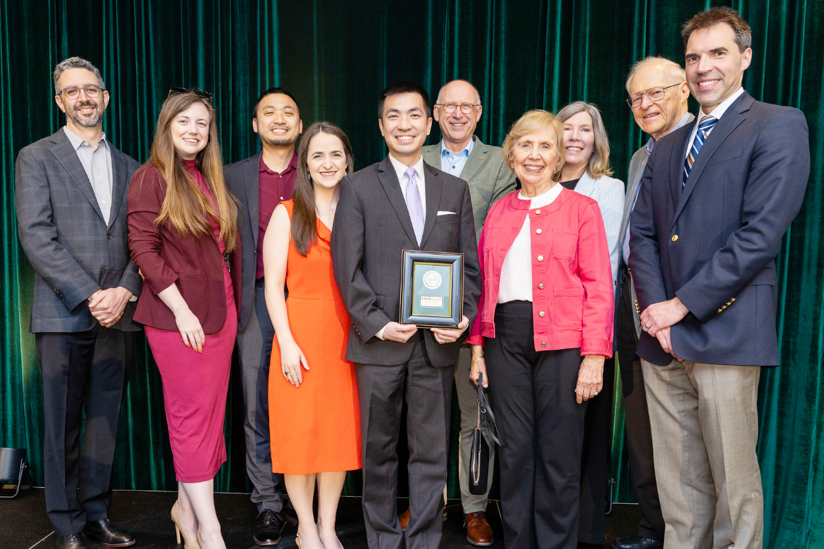 Dr. Liu holding award surrounded by colleagues and family smiling for a group photo