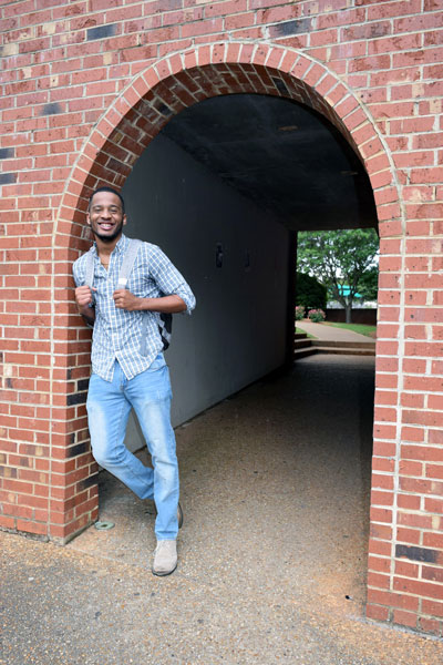 Rashad Hayes standing under a brick archway.