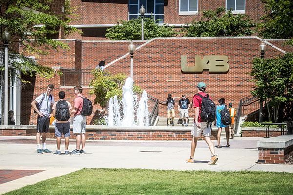 Students standing in front of building with UAB sign.