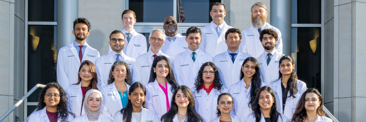A group of people in white coats stand in four rows.