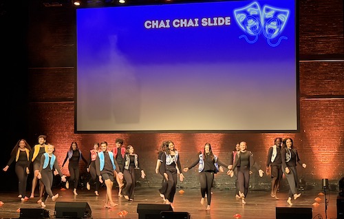 A group of medical students performing a choreographed dance on stage.