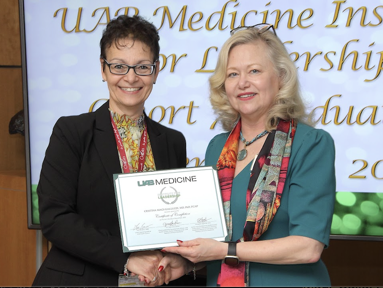 Magi-Galluzzi shaking hands with Jean Ann Larson and holding a graduate certificate