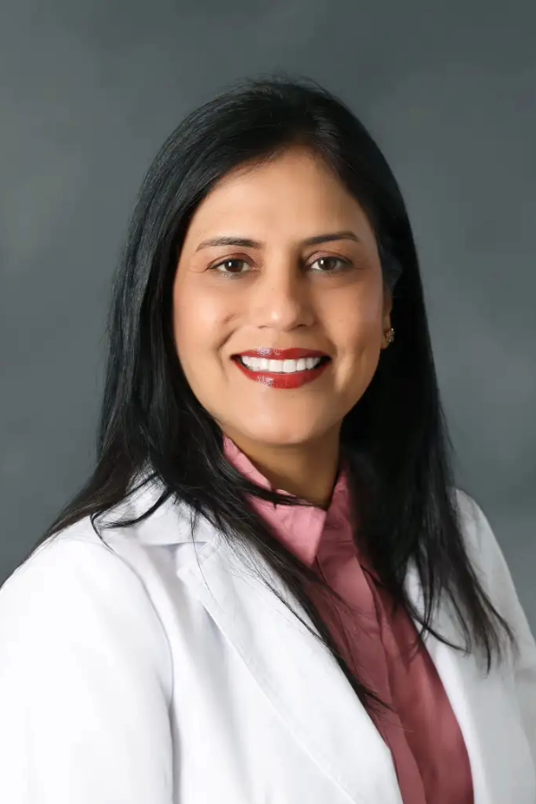 Shivani Malhotra, M.D., stands in front of a gray background.