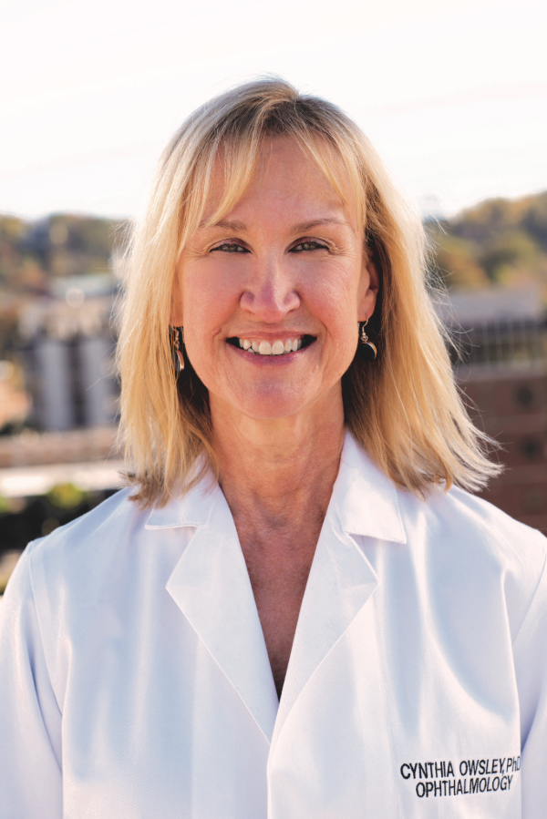 Cynthia Owsley, Ph.D., stands outdoors in front of buildings.