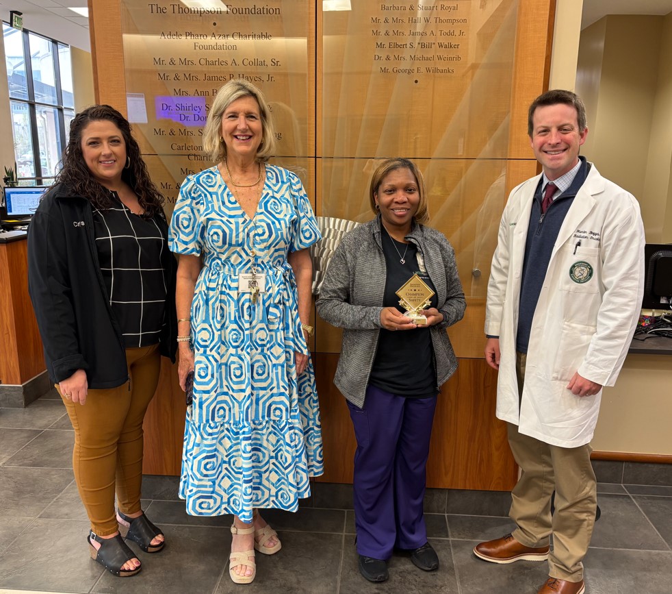 Four people standing in a hallway with the champion of safety, Tasha White, holding a plaque