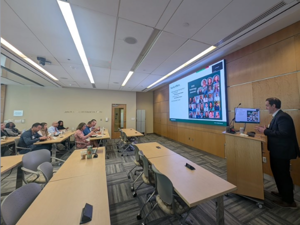 Dr. Mossa-Basha standing at a podium presenting to a room of faculty, staff, and trainees. 