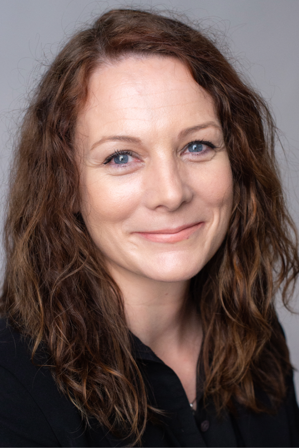 Elizabeth Worthey, Ph.D., stands in front of a gray background.