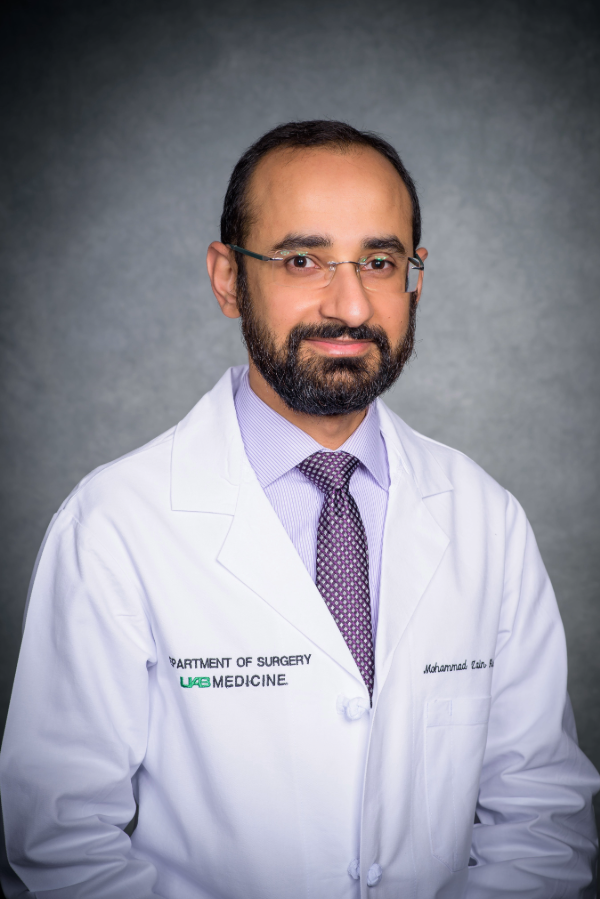 Zain Hashmi, M.D., stands in front of a gray background.