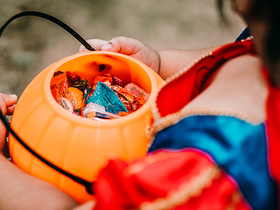 Baby girl holding candies in pumpkin basket