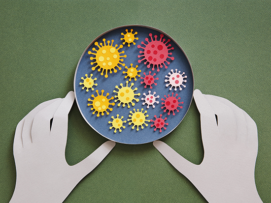 Conceptual paper illustration of human hands and coronavirus in a lab. Flat lay top-down composition on green background.