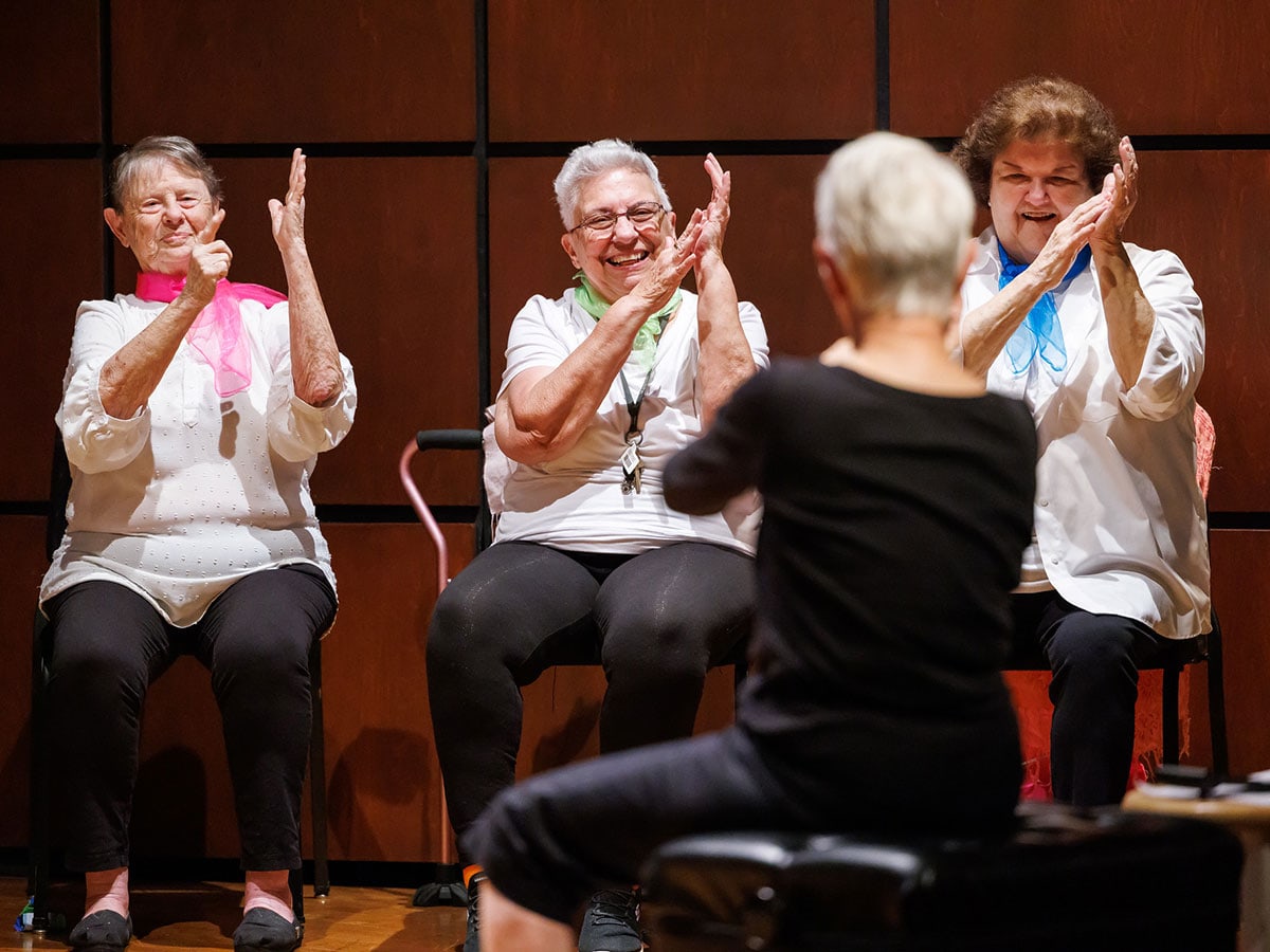 Woman guiding seniors through an acting exercise.