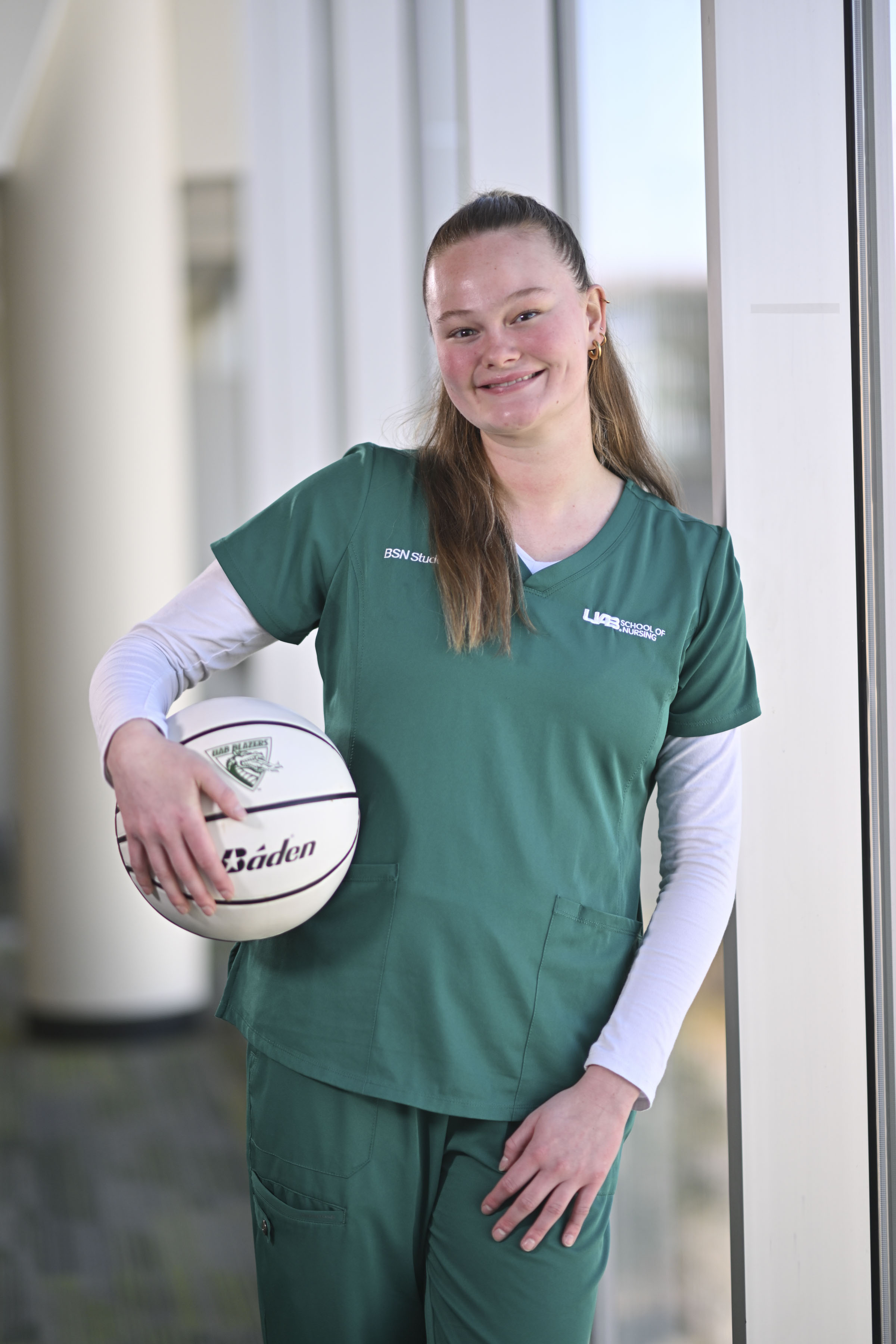 Interior image of Molly Moffitt wearing green scrubs and holding a white basketball.