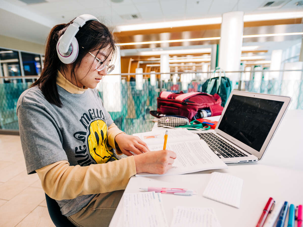 student sitting at table wearing headphones while studying