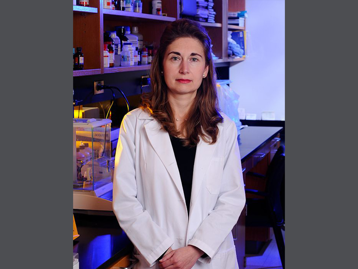 Anath Shalev, M.D., standing in front of a laboratory background