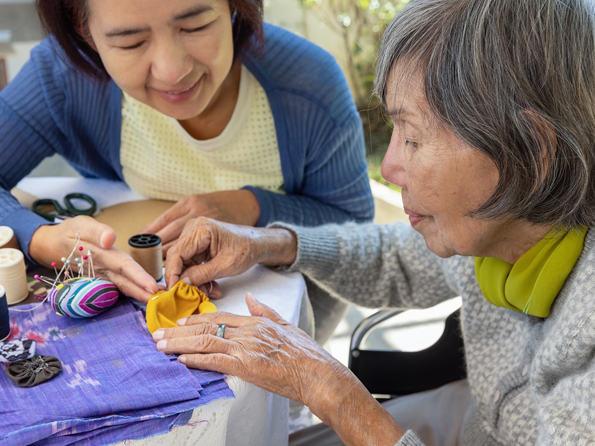 An older woman and a younger woman work on a sewing project