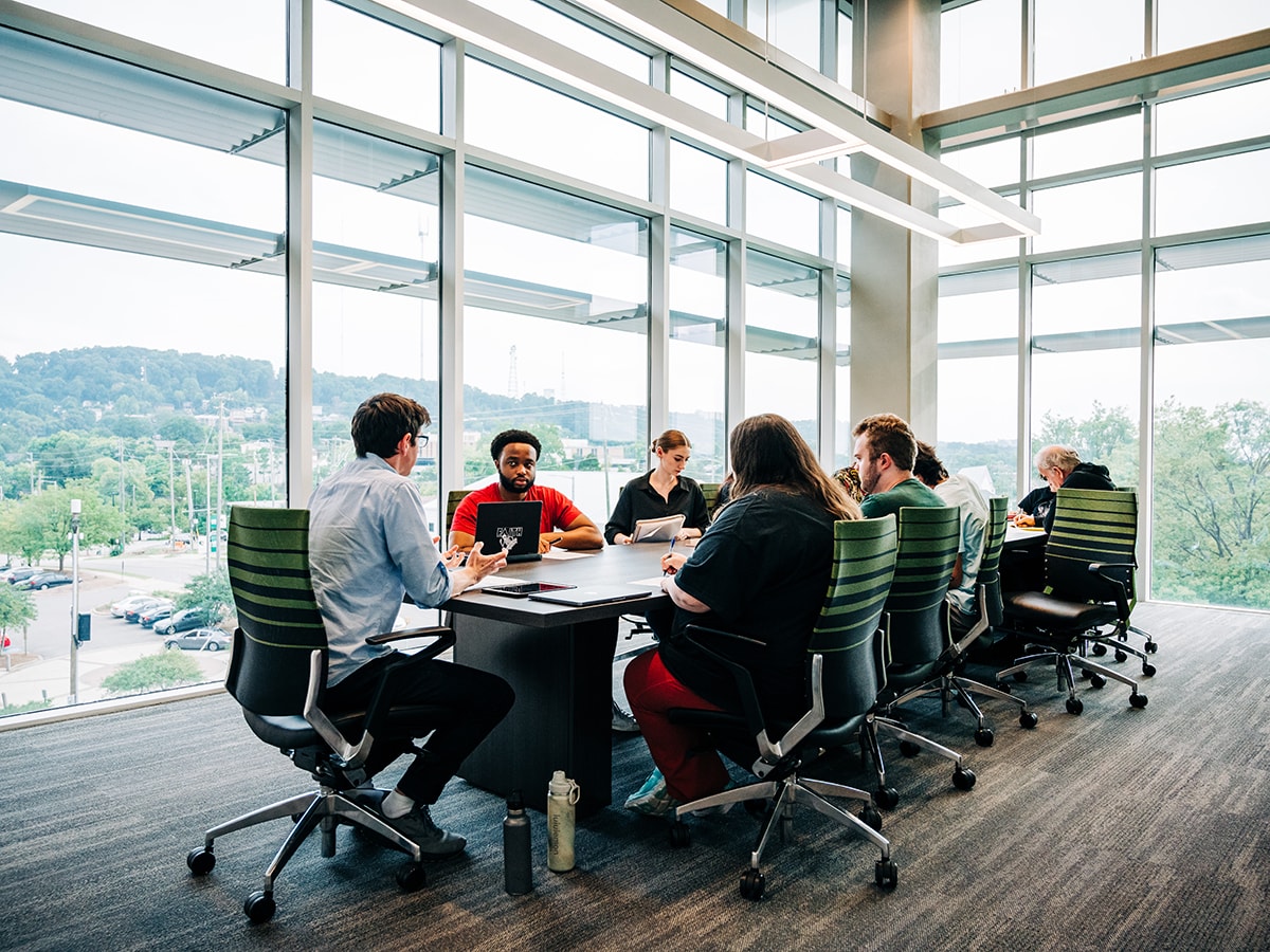 Joshua May, Ph.D., seated at head of a conference table in a UAB classroom talking to students in a philosophy course