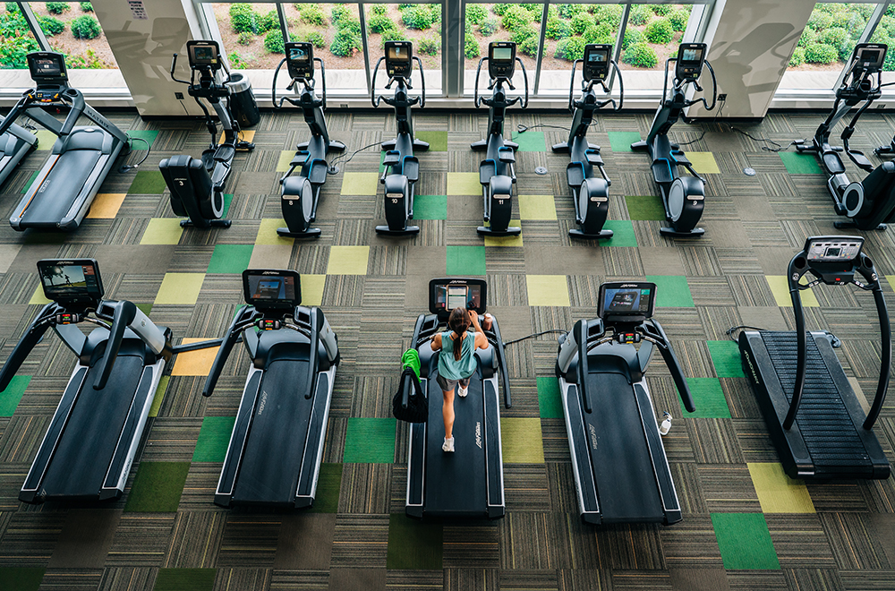 Overhead view of a single student running on a treadmill at the Rec Center, surrounded by empty treadmills and step machines