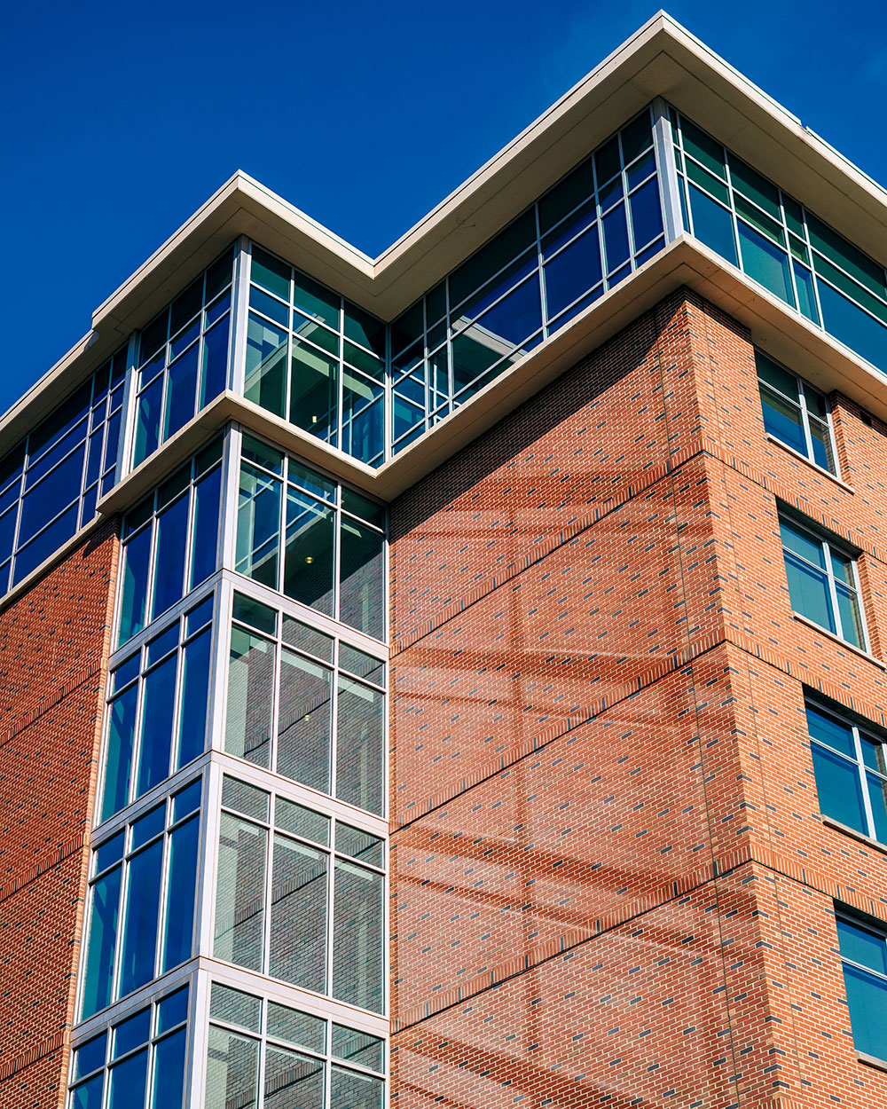 Vertical image of the upper floors of Blazer Hall, seen from below, silhoutted against a blue sky
