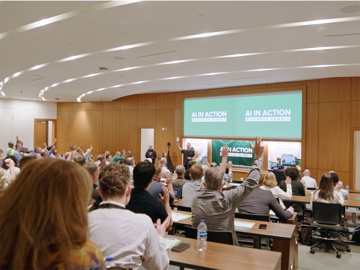 Audience members raise hands with questions at the AI in Action: Business Summit at the Collat School of Business in April 2026