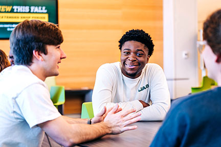 Three students, one looking at viewer, talk in University Hall