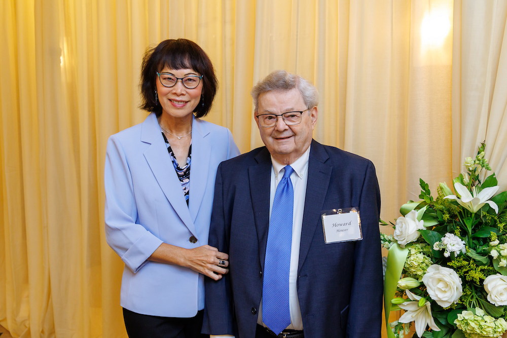 Shannon Houser with a light blue blazer stands next to her husband Howard who is wearing a dark blue blazer and blue tie.