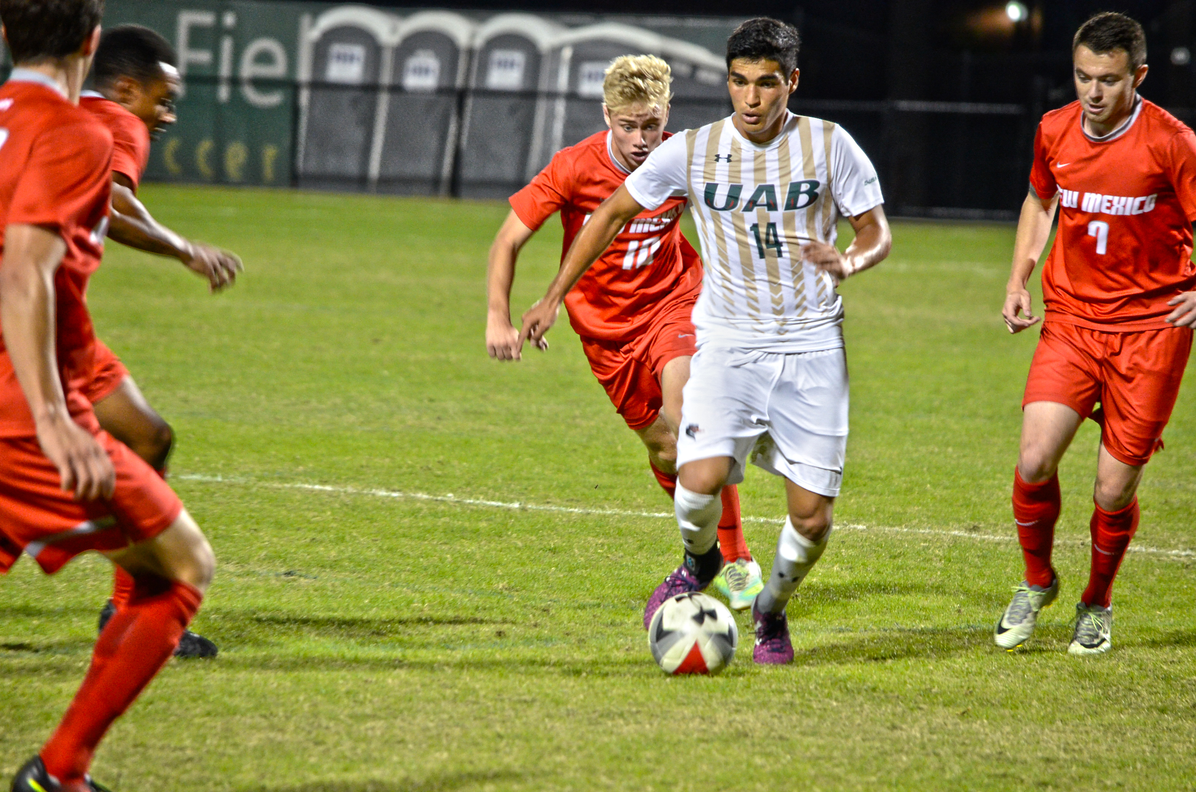 Junior midfielder David Valverde of Mobile dribbles the ball past oncoming Lobos defenders in Wednesday night’s game against the No. 30 New Mexico Lobos. Photo by Ian Keel