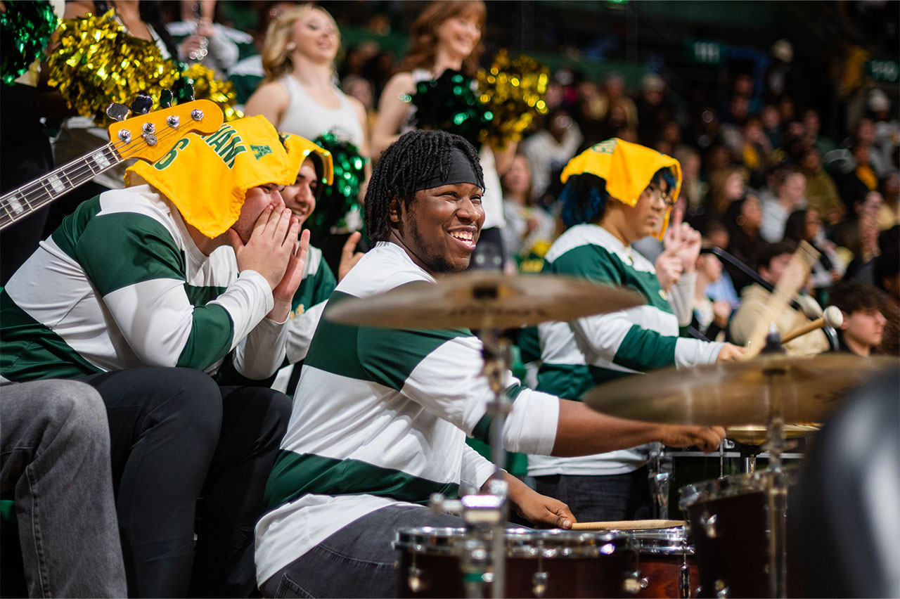 Band members play instruments and cheer during a basketball game.